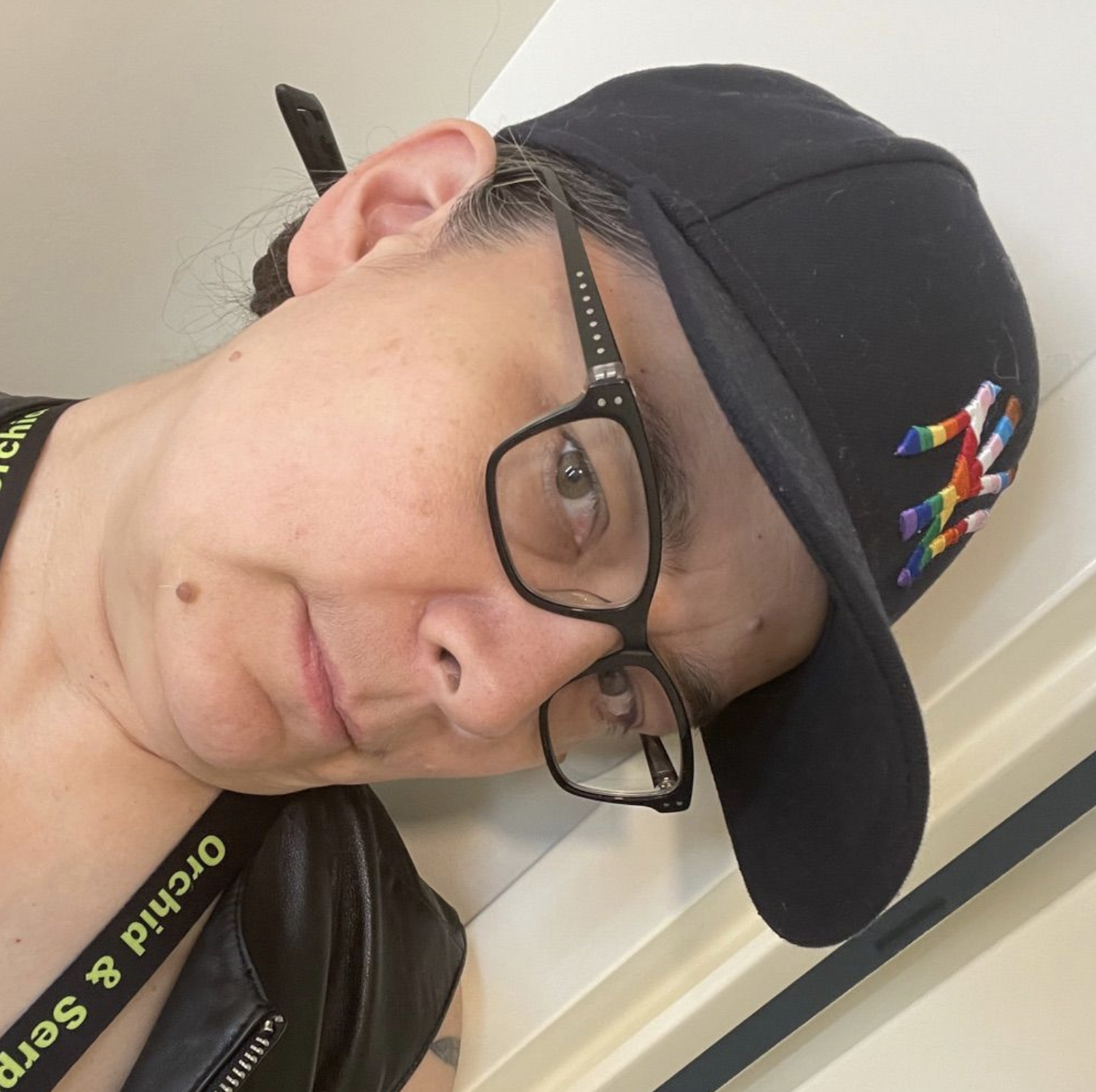 Person with glasses with a rainbow NY Yankees cap